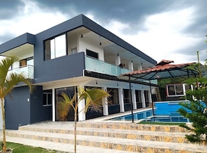 Ein modernes, zweistöckiges Haus mit Swimmingpool, Steinstufen und einer überdachten Terrasse.