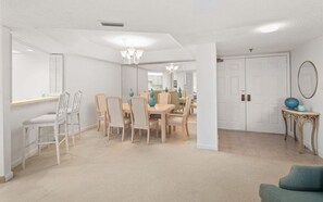 A spacious living area with a dining table, chairs, a chandelier, and a door.