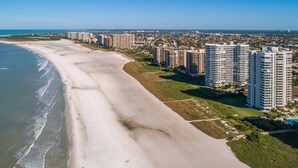Un paisaje urbano costero con una amplia playa de arena, edificios altos y un cielo azul despejado.