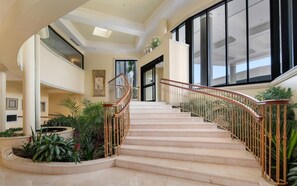 Stunning staircase with lush greenery and framed artworks adorns the entrance.