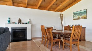 Zona pranzo con tavolo e sedie in legno, camino e un quadro appeso al muro.