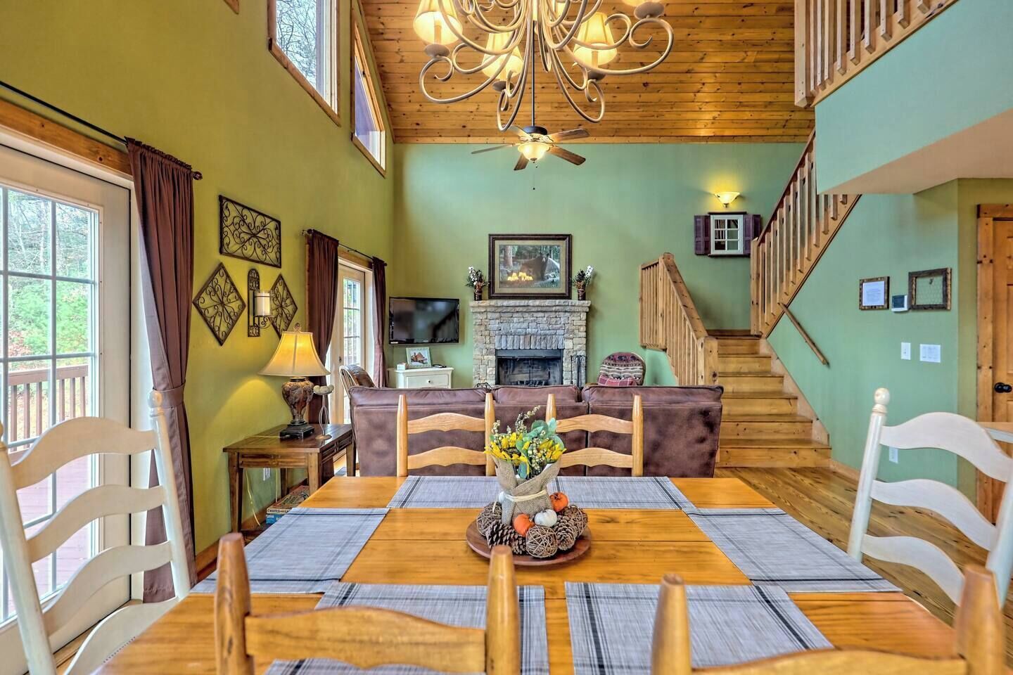 A dining area with a wooden table and chairs, a fireplace, and a staircase leading to another level.