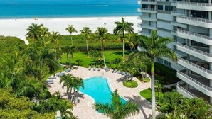 Un resort con piscina, rodeado de palmeras y vistas a la playa.