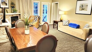 Habitación de hotel con comedor, sofá, lámpara y chimenea.