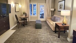 Una habitación de hotel con sofá, una mesita con una planta, televisor y lámpara.