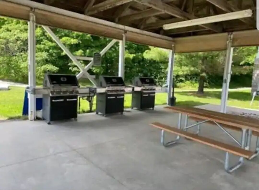 A covered picnic area with barbecue grills and a picnic table.