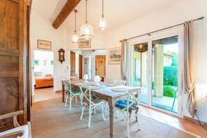 A dining area with a wooden table, white chairs, and hanging pendant lights.