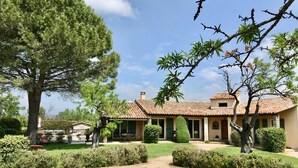 Une villa de style méditerranéen, dotée d’un toit en tuiles, d’une piscine et de jardins bien entretenus.