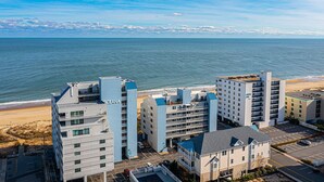 Un complesso alberghiero sulla costa con diversi edifici, tra cui un cartello 'CEANA' ben visibile, affiancato da una spiaggia e vista libera sull'oceano.