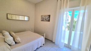 A bedroom with a bed, a mirror, a picture on the wall, and a view through a window. - La Perla Apartment (Sant'Agnello)