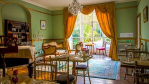 A dining room with a chandelier, wooden furniture, and a view through large windows. - Plas Dolguog (Machynlleth)