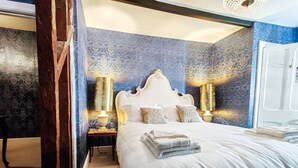 A bedroom with a large bed, two bedside lamps, and a door. - Plas Dolguog (Machynlleth)