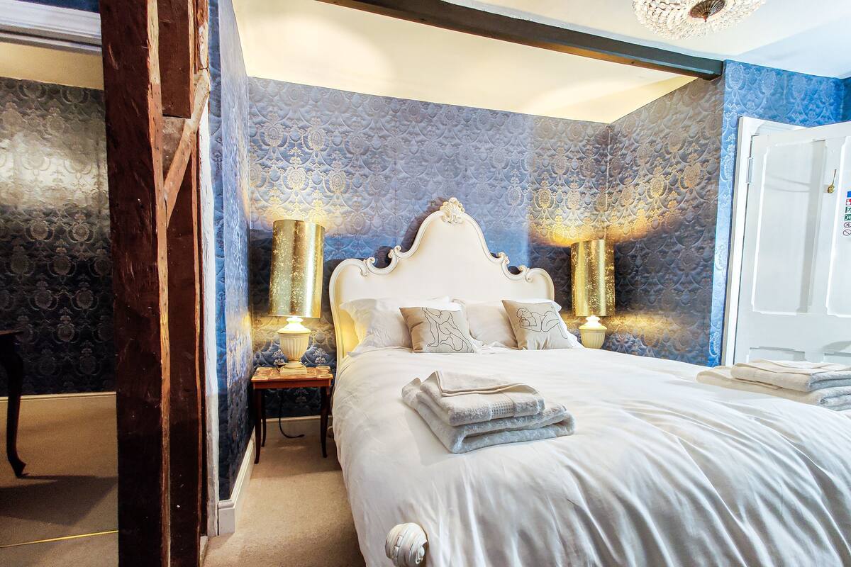 A bedroom with a large bed, two bedside lamps, and a door.