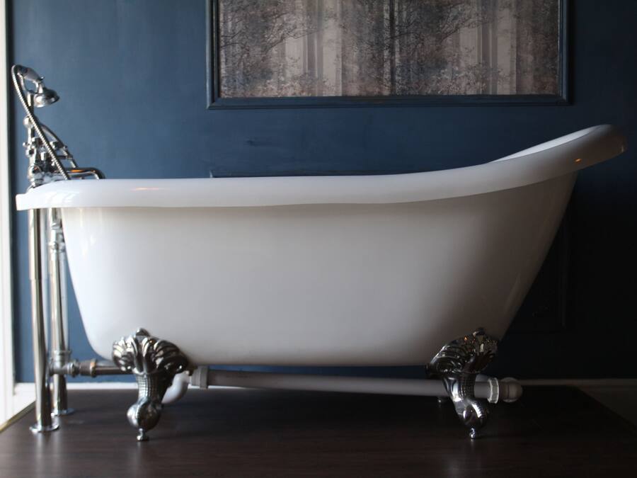 A freestanding bathtub with ornate legs, a white interior, and a blue wall with a framed picture above it.