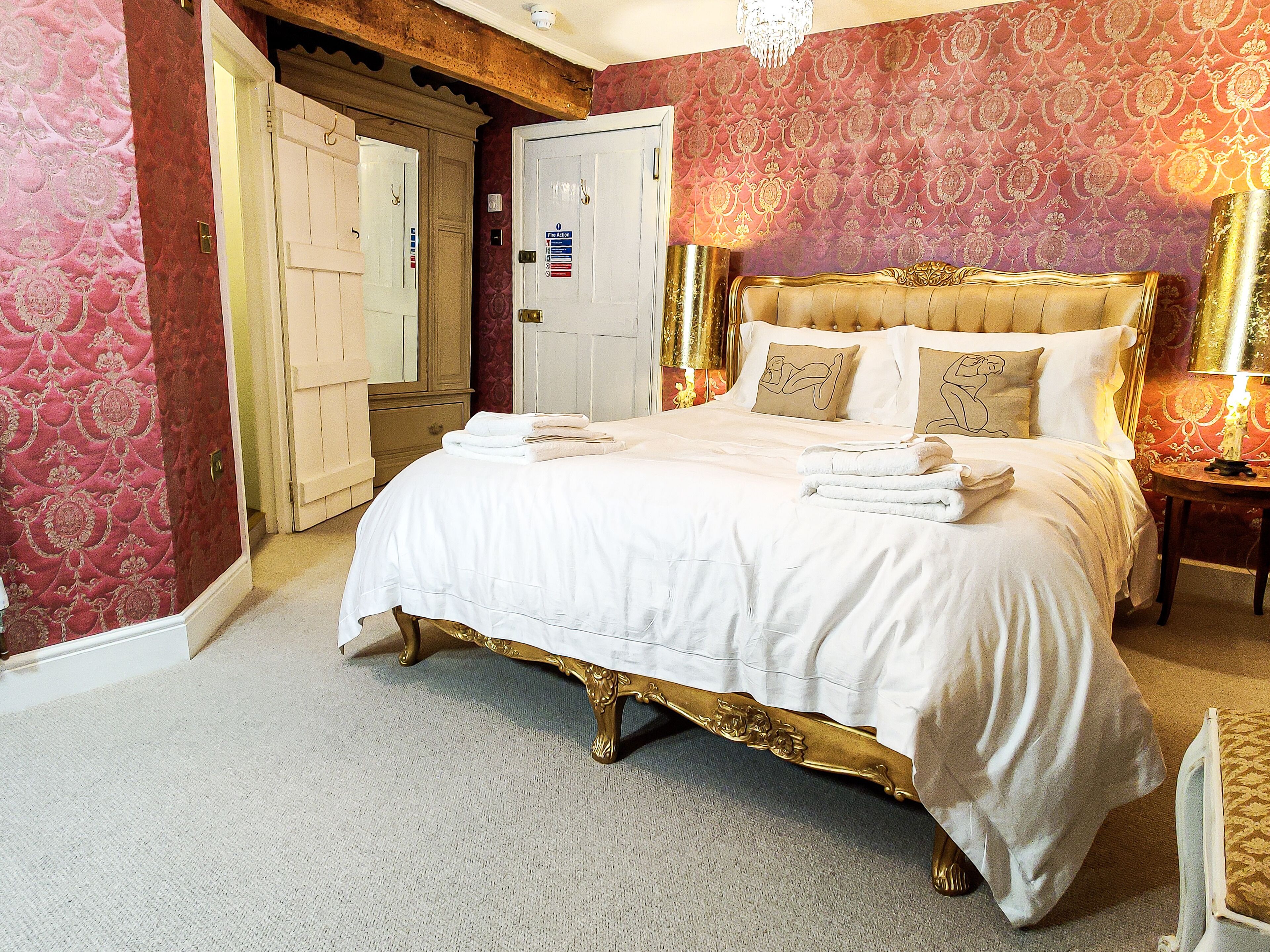 Ein Hotelzimmer mit einem großen Bett, einer Kristalllüster und einer Wand mit rotem Muster.