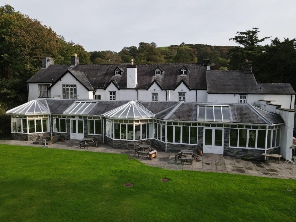 A large house with multiple gabled extensions, a conservatory, and a well-maintained lawn.