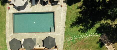 An aerial view of a swimming pool with surrounding umbrellas and a stone pathway.