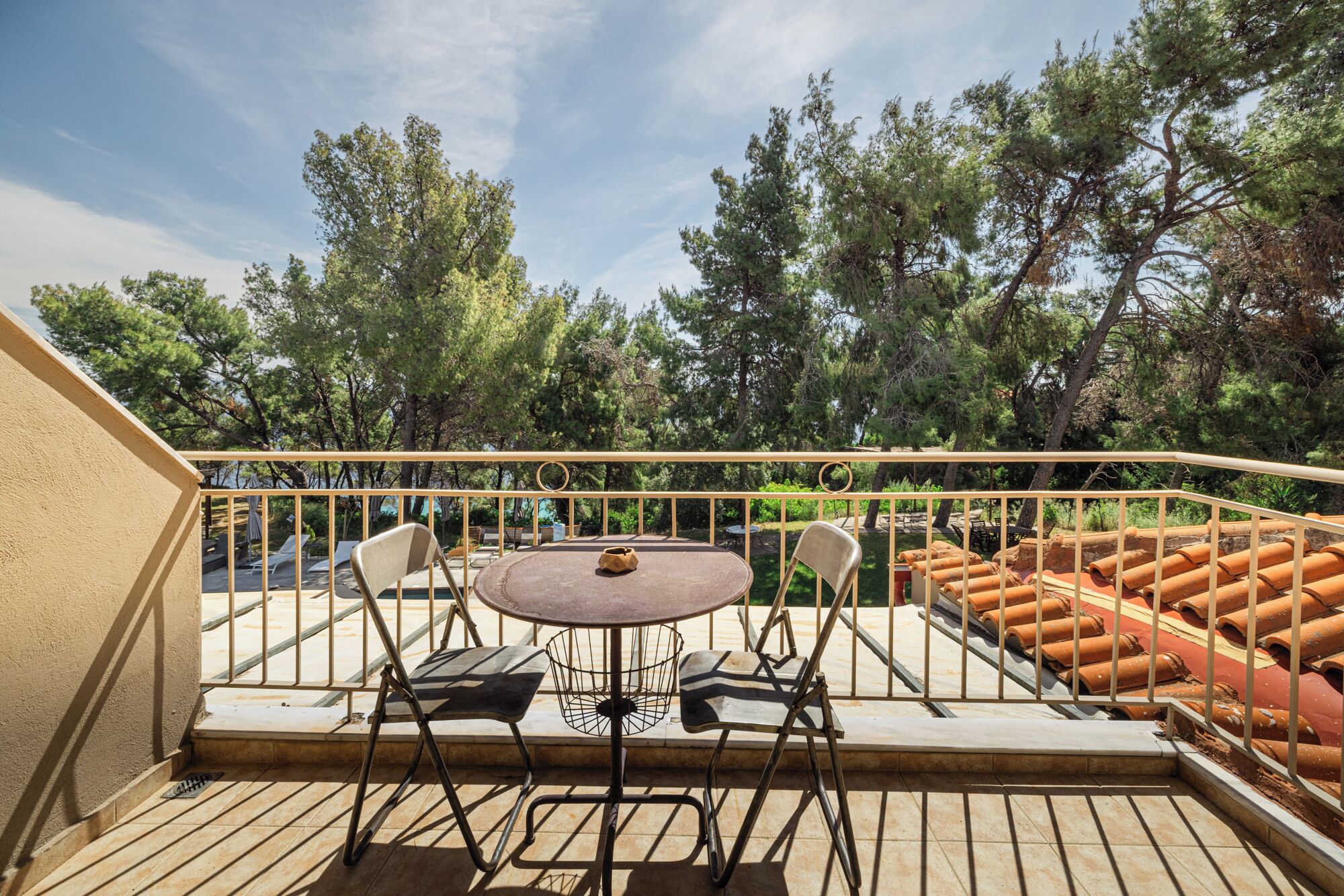 A wooden deck with a round table and four chairs, surrounded by a metal railing.