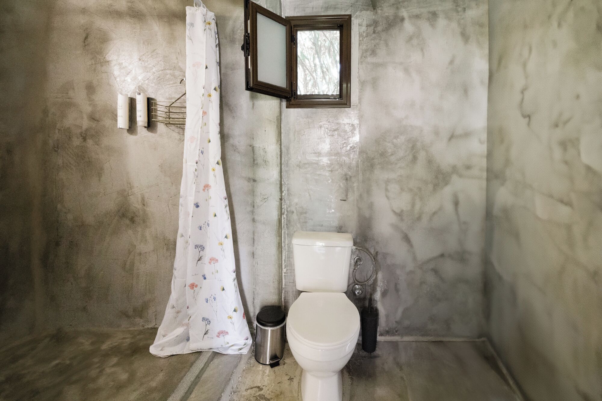 Un baño con inodoro, cortina de ducha y ventana.