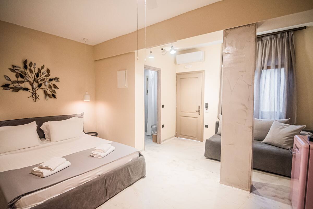 Une chambre d’hôtel comprenant un lit, un canapé, une petite table et un élément décoratif mural.