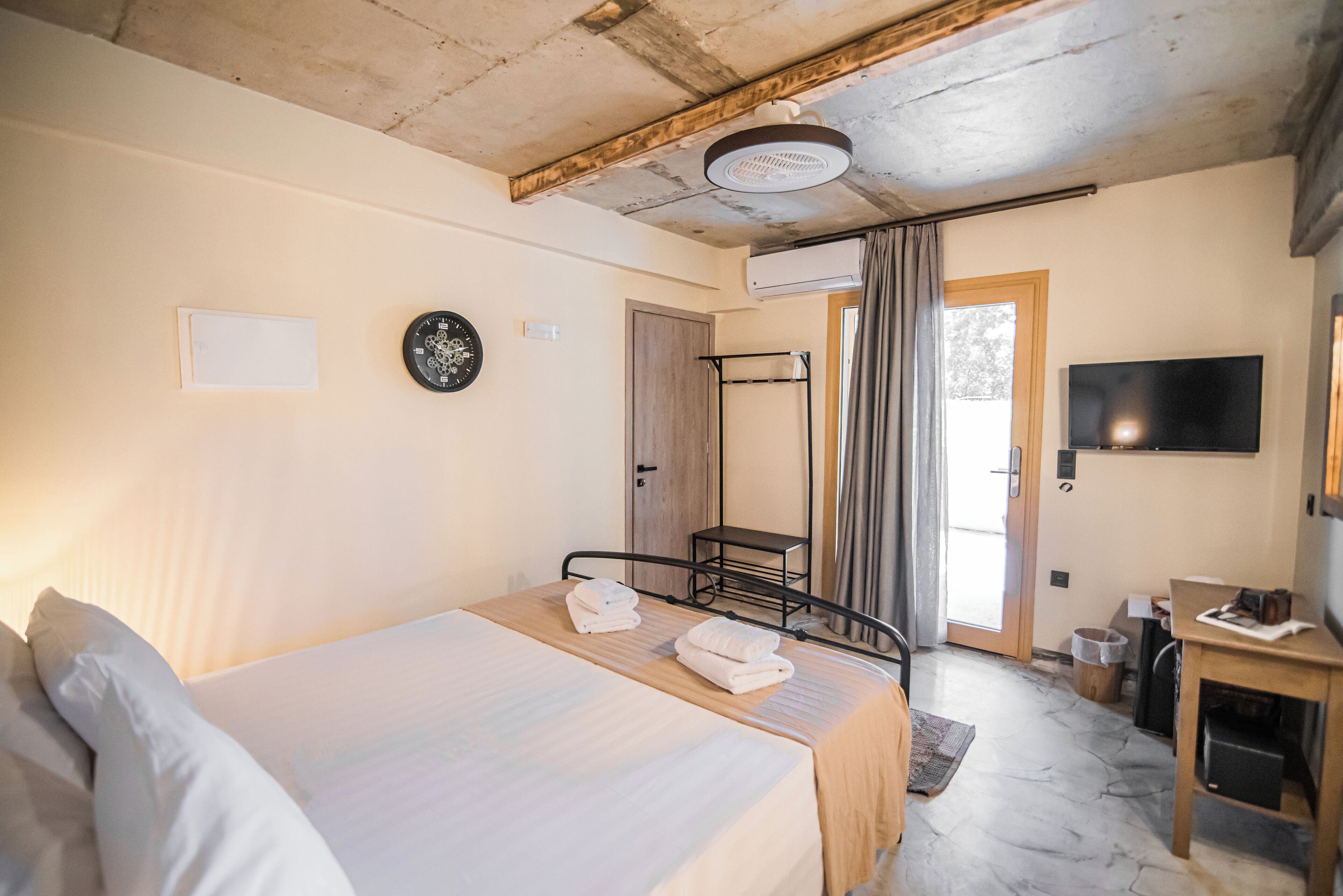 A bedroom with a bed, a bedside table, a TV, and a bathroom with a shower.