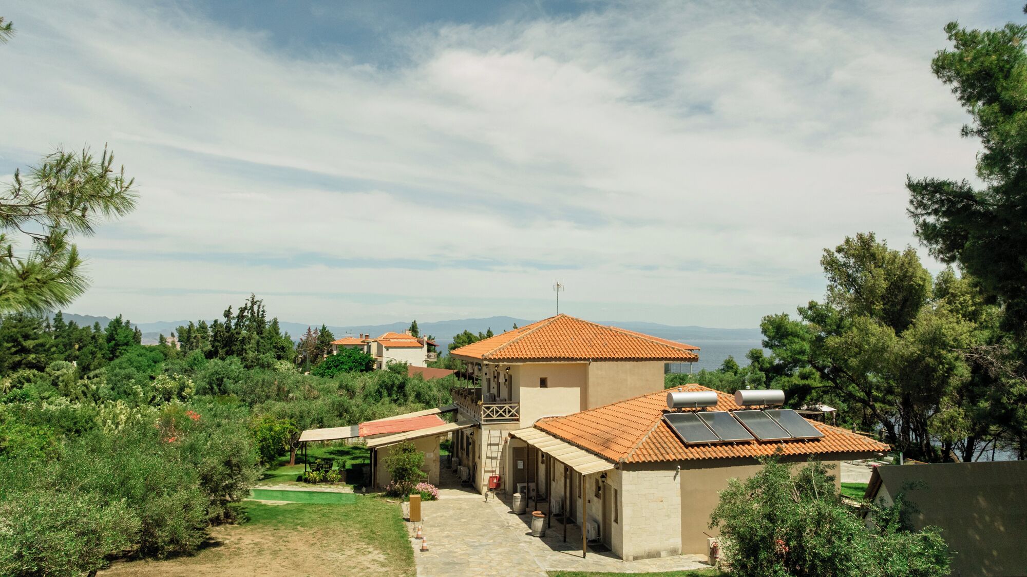 Una villa con techo de tejas, paneles solares y vista al mar.