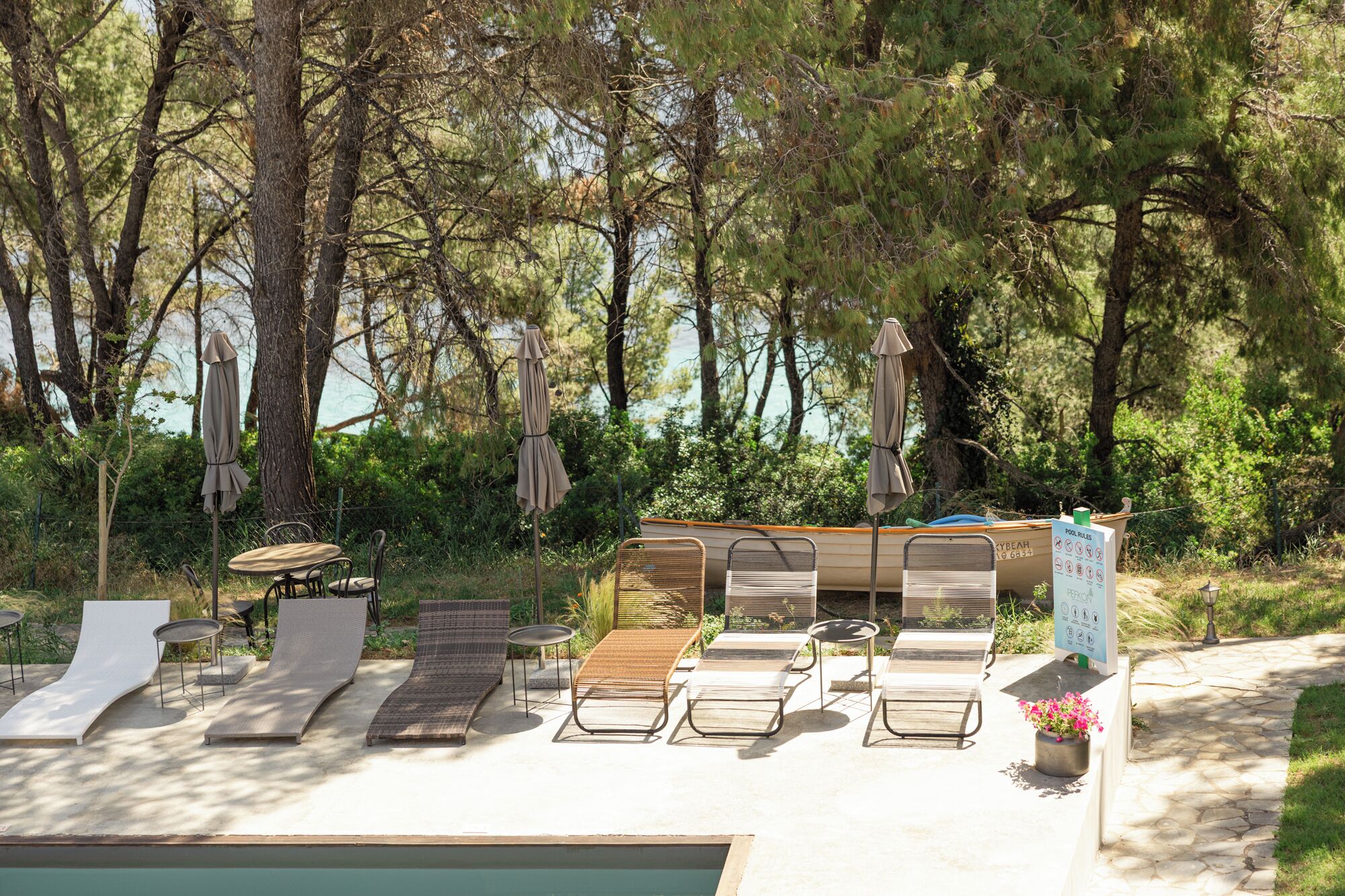 A poolside area with lounge chairs, a small table, and a covered seating area.