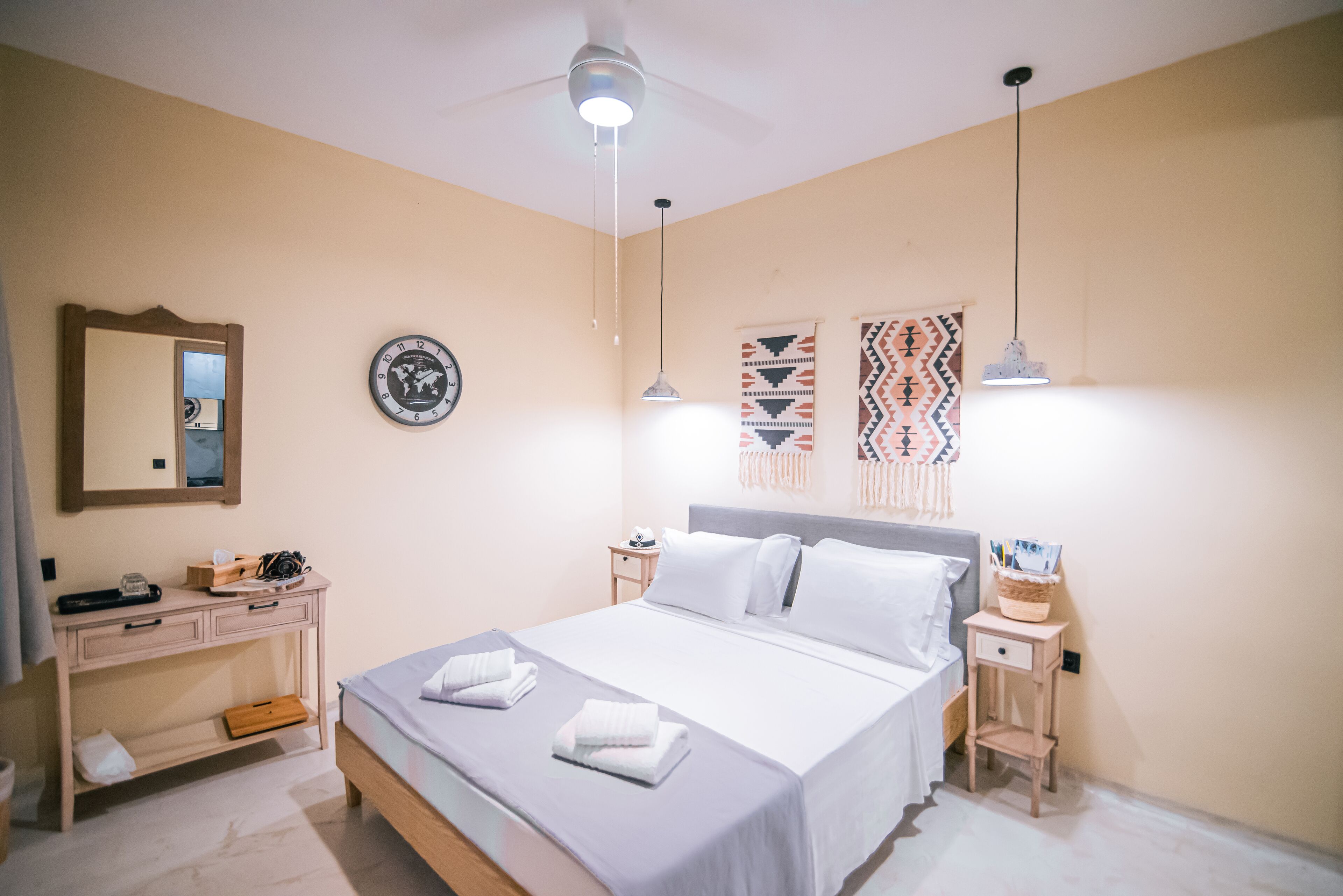 A neatly arranged bedroom with a bed, bedside tables, a dresser, and a mirror.