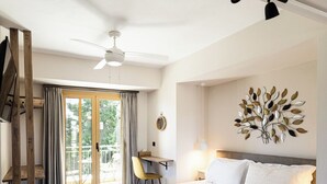 A modern bedroom with a large bed, a desk, a chair, and a view of the outdoors.
