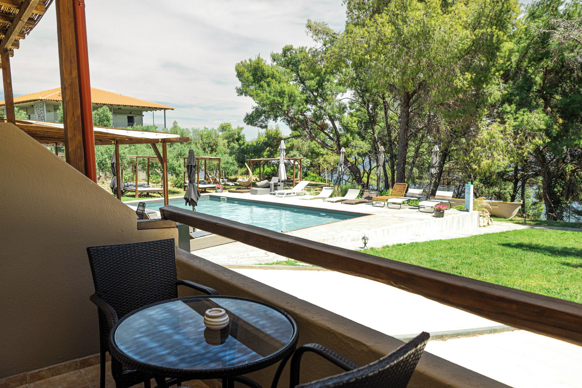 A balcony with a pool, lounge chairs, and a table.