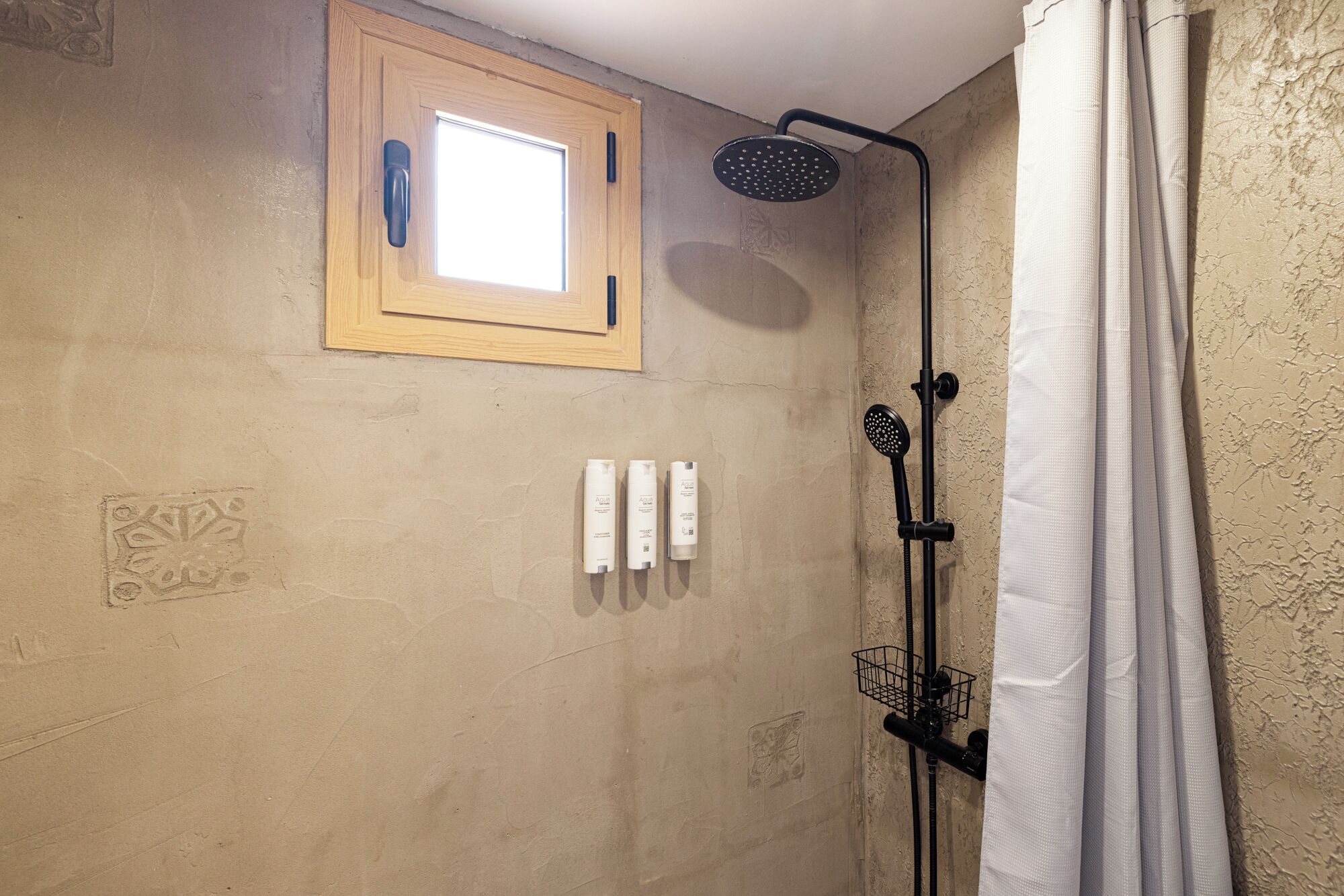 A bathroom with a shower, a window, and toiletries.