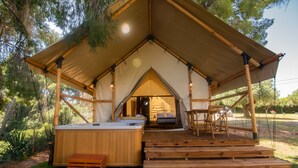 A tent with a wooden deck and hot tub.