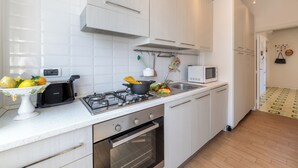 A modern kitchen with white cabinets, a gas stove, a microwave, and a sink. - Amazing apt with breathtaking seaview&Vesuvius in Sorrento center near the beach (Sorrento)