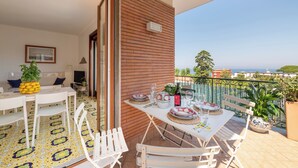 An outdoor dining area with a table set for four, white chairs, and a view of the sea. - Amazing apt with breathtaking seaview&Vesuvius in Sorrento center near the beach (Sorrento)