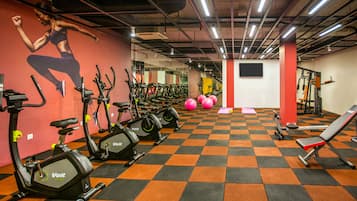Un gimnasio con bicicletas estáticas, una banca y pelotas de ejercicio.
