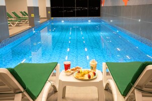 Una piscina interna con sedie a sdraio e un tavolo imbandito con cibo e bevande.