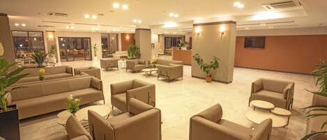 Un vestíbulo amplio con varias zonas de estar, incluyendo sofás y sillones, y una recepción.