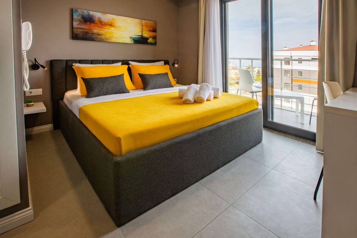 Een hotelkamer met een groot bed, een schilderij aan de muur en een balkon met uitzicht.