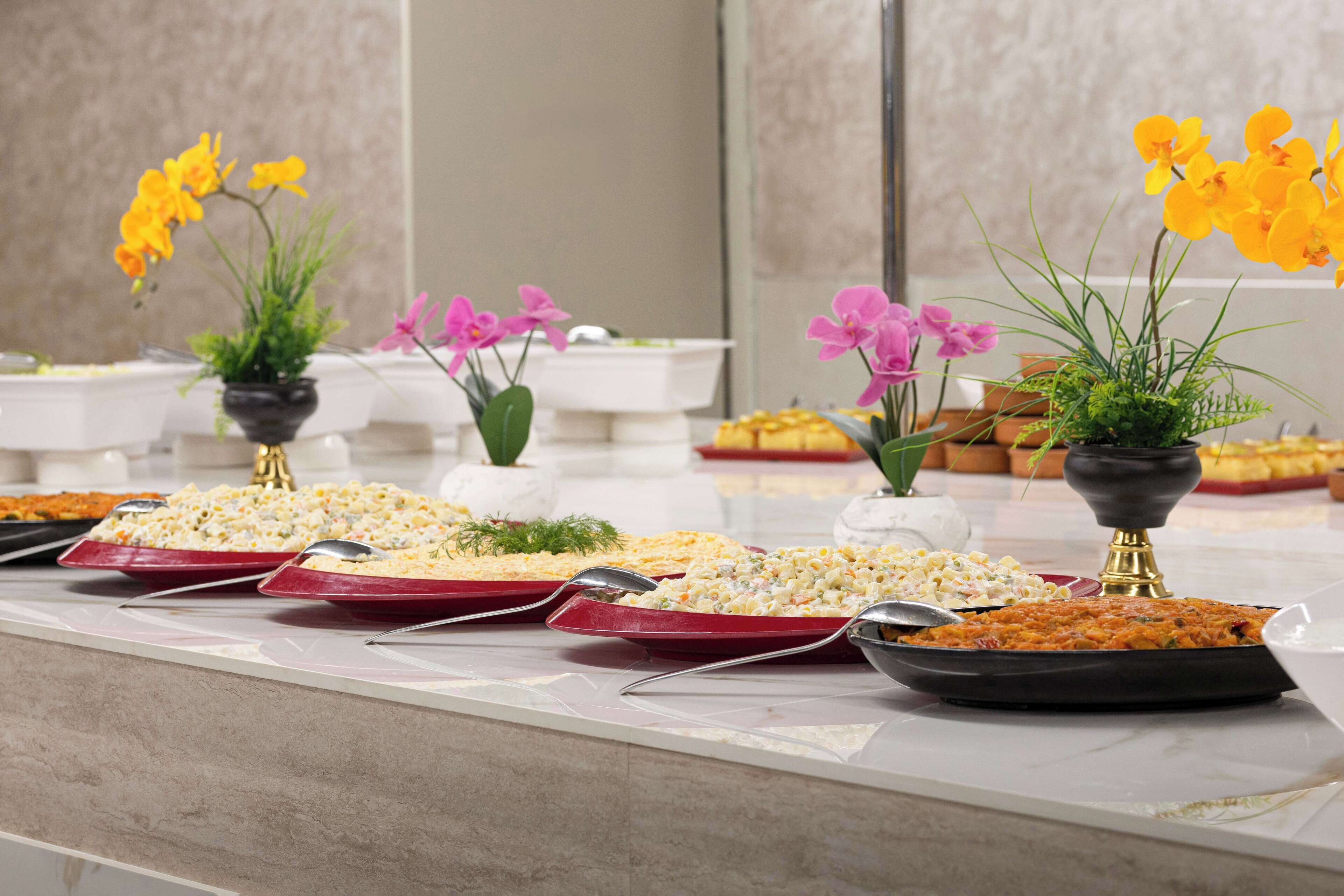 Une table de buffet garnie de divers plats et agrémentée de plantes en pot.