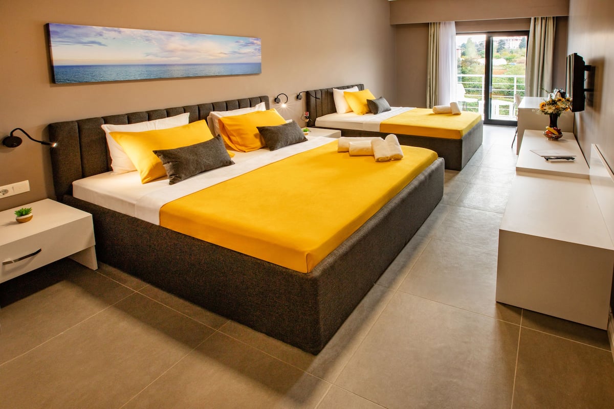 Een hotelkamer met twee bedden, een bureau, een stoel, een televisie en een schilderij aan de muur.