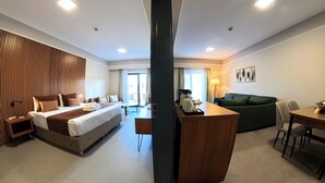 A hotel room with a large bed, a sofa, a dining table, and a kitchen area. - First Joy Hotel (Trabzon)