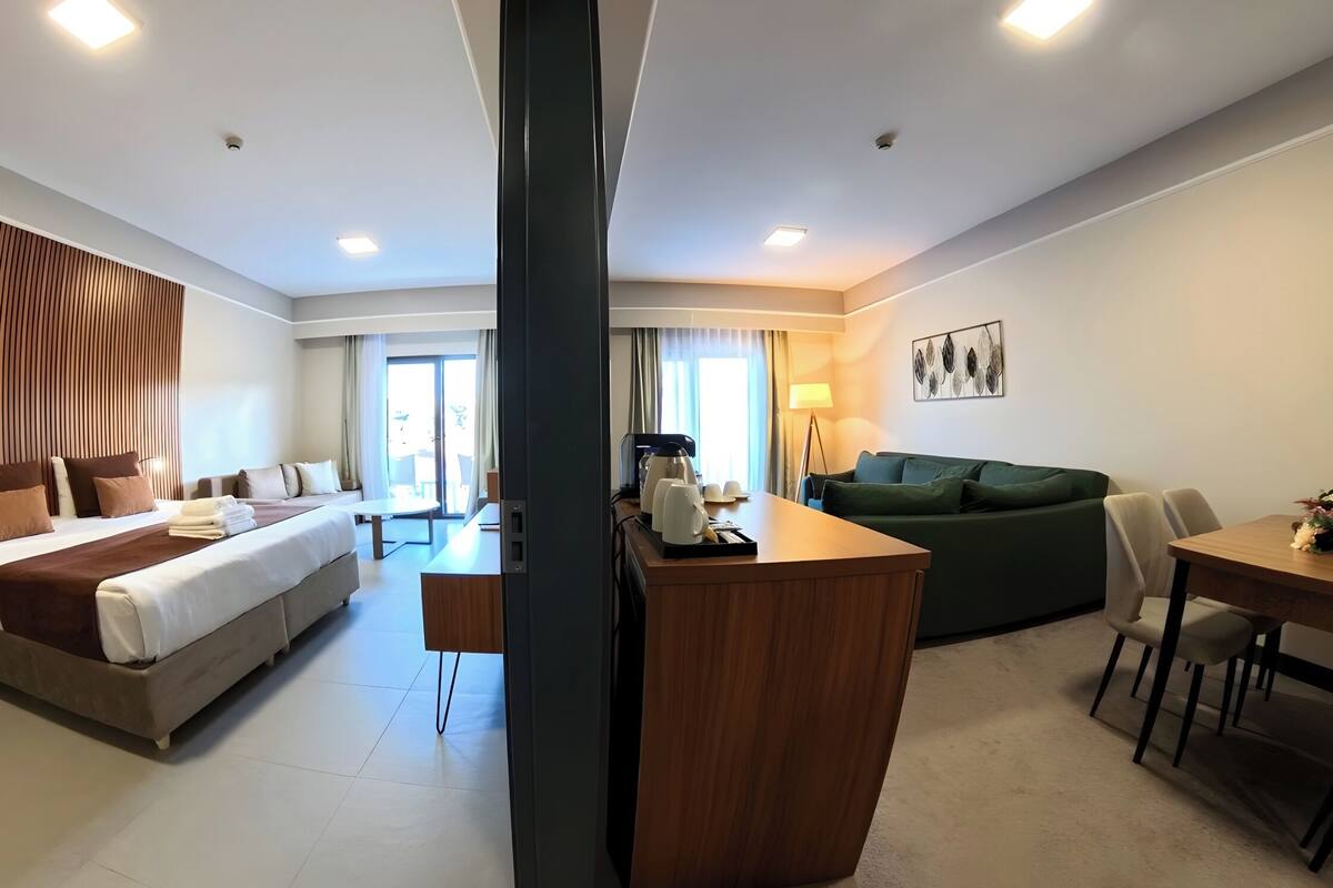 Een hotelkamer met een groot bed, een bank, een eettafel en een keukenhoek.