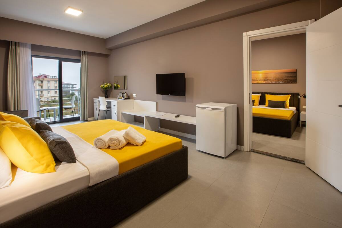Een moderne hotelkamer met een groot bed, een bureau, een flatscreen-televisie en een balkon met uitzicht op de stad.