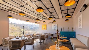 A spacious dining area with high ceilings, modern pendant lighting, and a view of the cityscape. - First Joy Hotel (Trabzon)