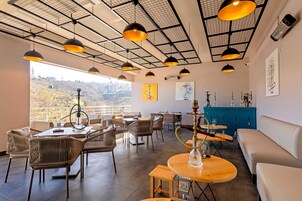 Un'ampia sala da pranzo con soffitti alti, lampade a sospensione moderne e vista sulla città.