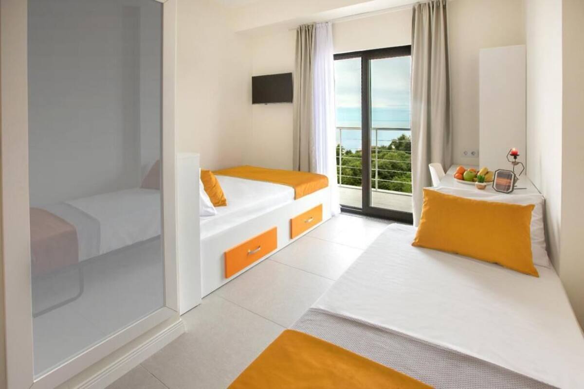 Een hotelkamer met een bed, een bank, een televisie en een balkon met uitzicht.