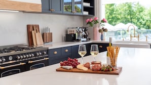 Een keuken met een marmeren aanrecht, een wijnfles en een glas witte wijn.