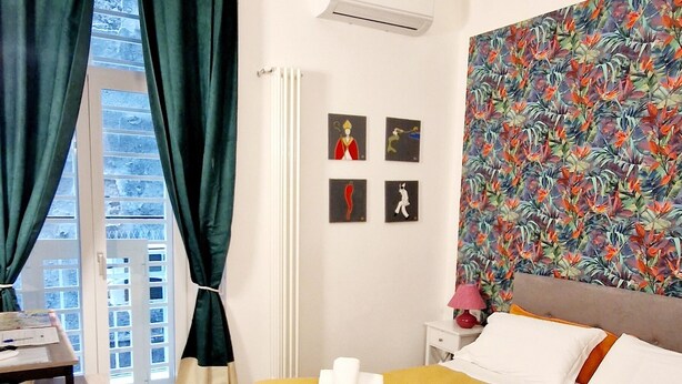A hotel room with a bed, a desk, and a window with curtains. - Tribunali Platamon (Naples)
