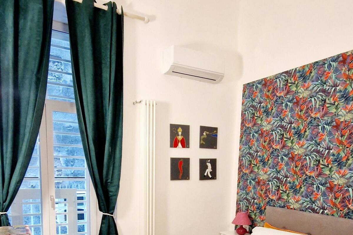 A hotel room with a bed, a desk, and a window with curtains.