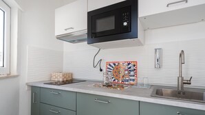 A modern kitchen with a microwave, stainless steel sink, and green cabinets. - Attico 37 Apartments (Palermo)